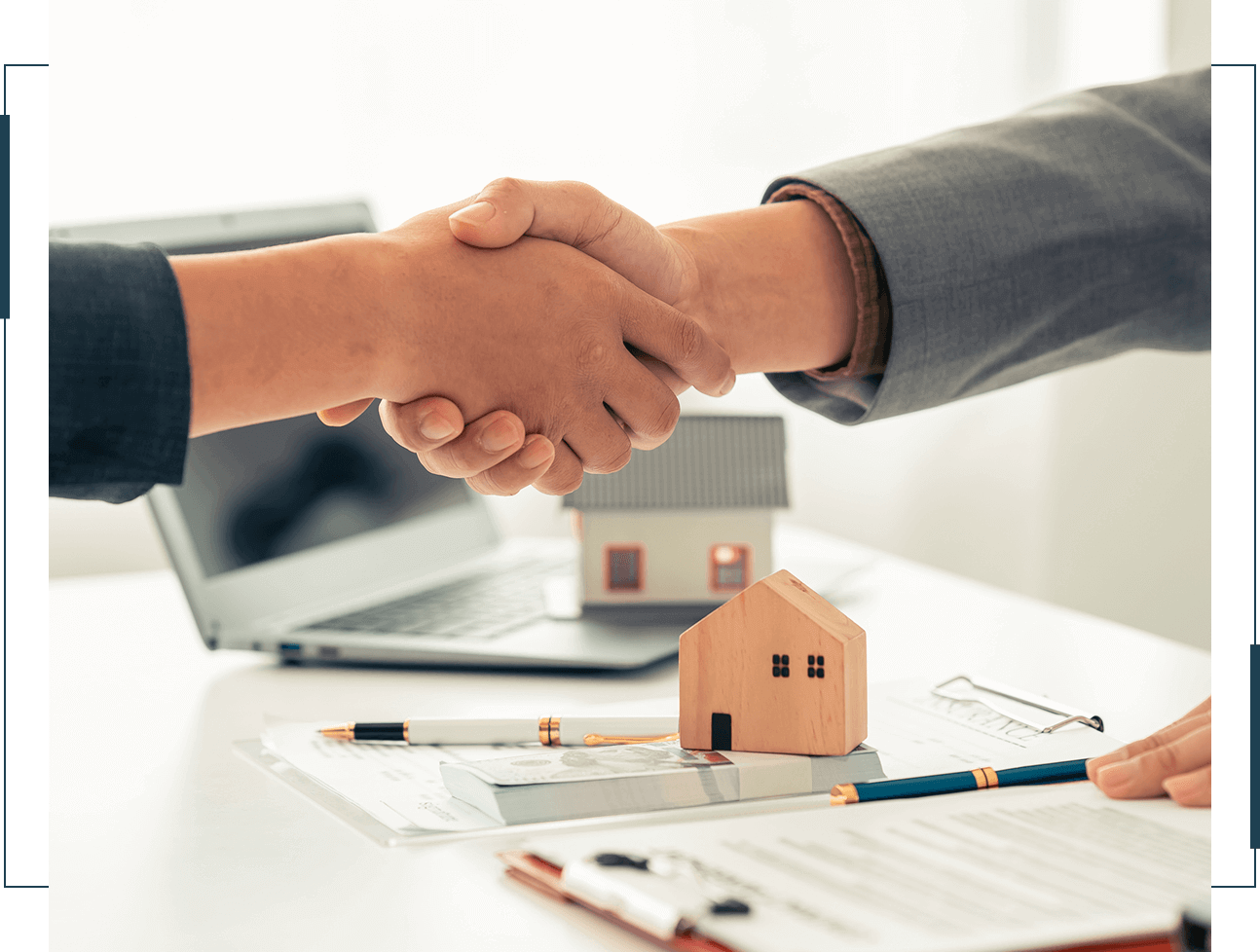Handshake over real estate contract and model house.