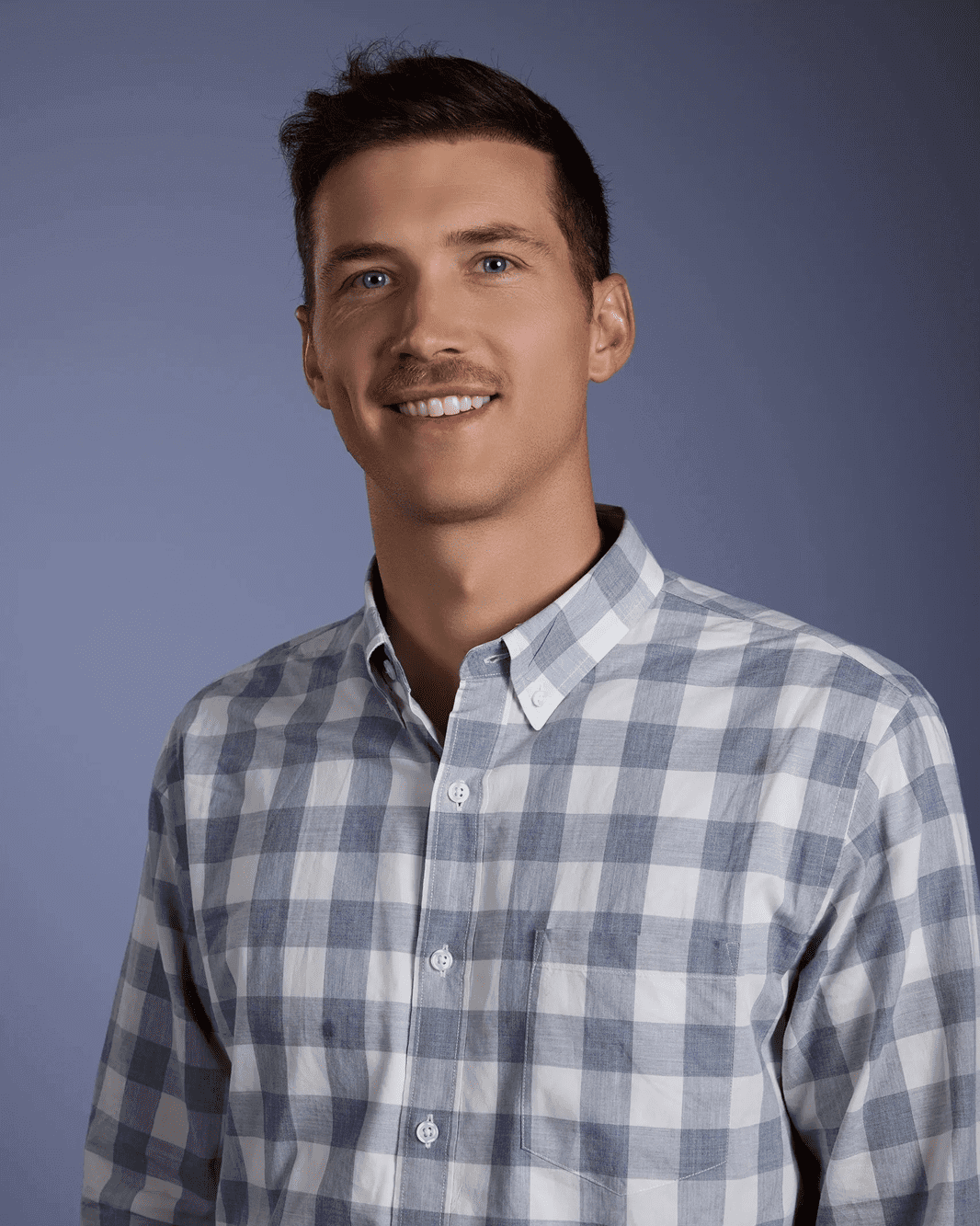 Man in checkered shirt, smiling, blue background.