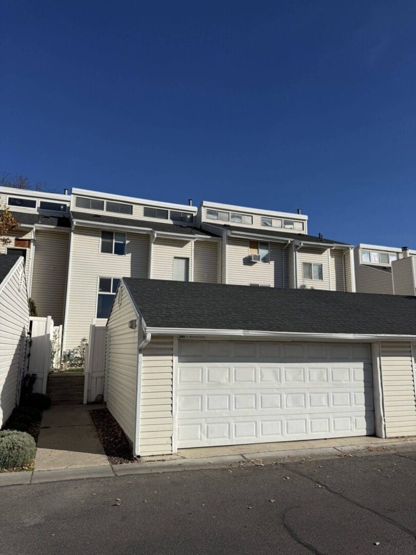 White townhouse with garage under clear sky.